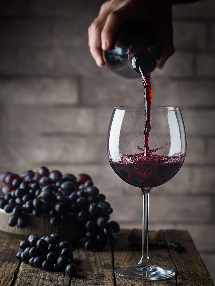 赤ワインをグラスに注ぐシーンとテーブルに置かれたぶどう